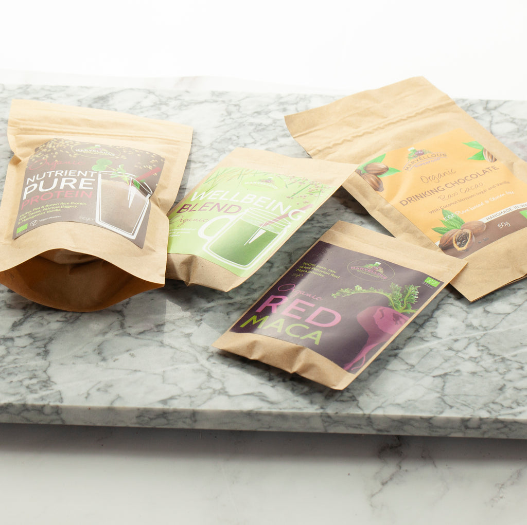 A selection of superfood pouches from the Superfood surprise box including our Wellbeing blend, Nutrient pure protein powder, organic Red Maca and organic drinking chocolate in 100% compostable packaging.